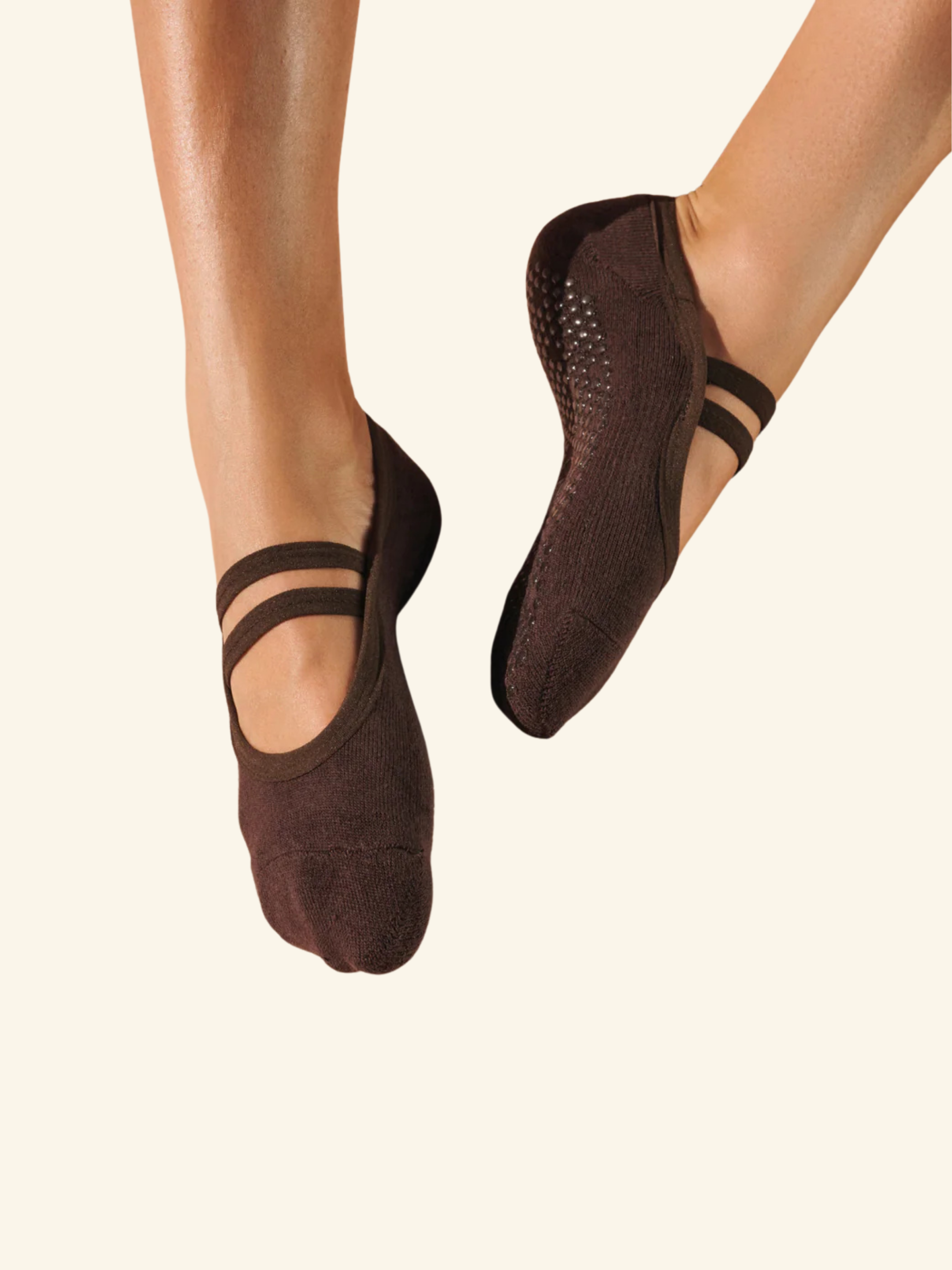Brown ballet flats worn by a person on a beige background