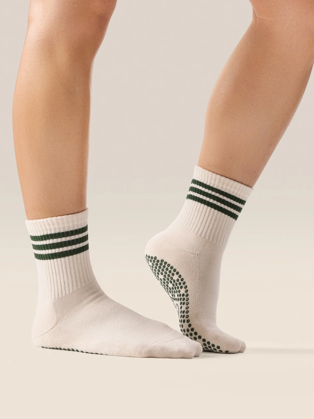 White socks with green stripes and black pattern on toes worn by a person on a neutral background