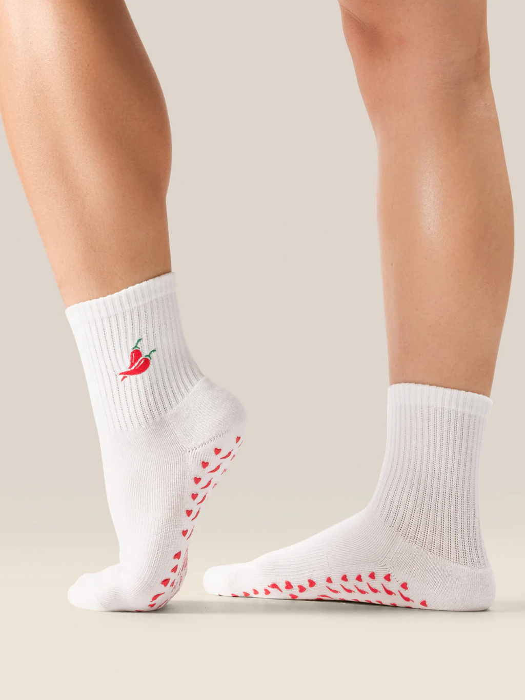 White socks with red patterns and a chili pepper design on a neutral background