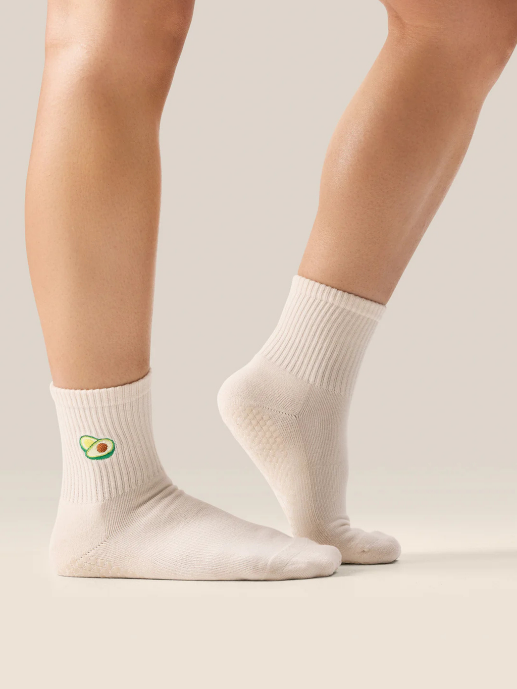 cute Pilates grip socks UK. White socks with avocado design worn by a person on a neutral background