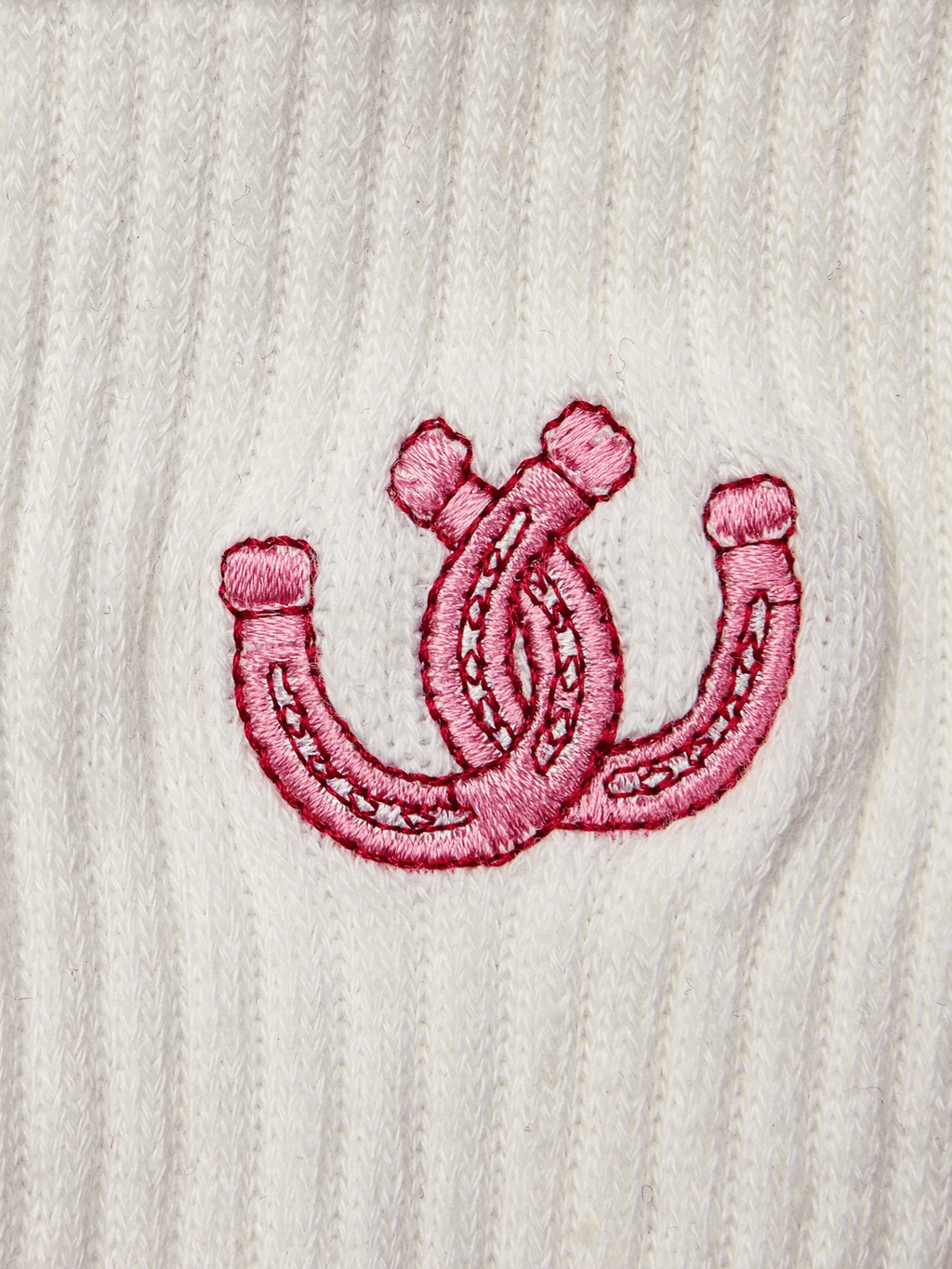Pink embroidered double horseshoe design on a white textured fabric background