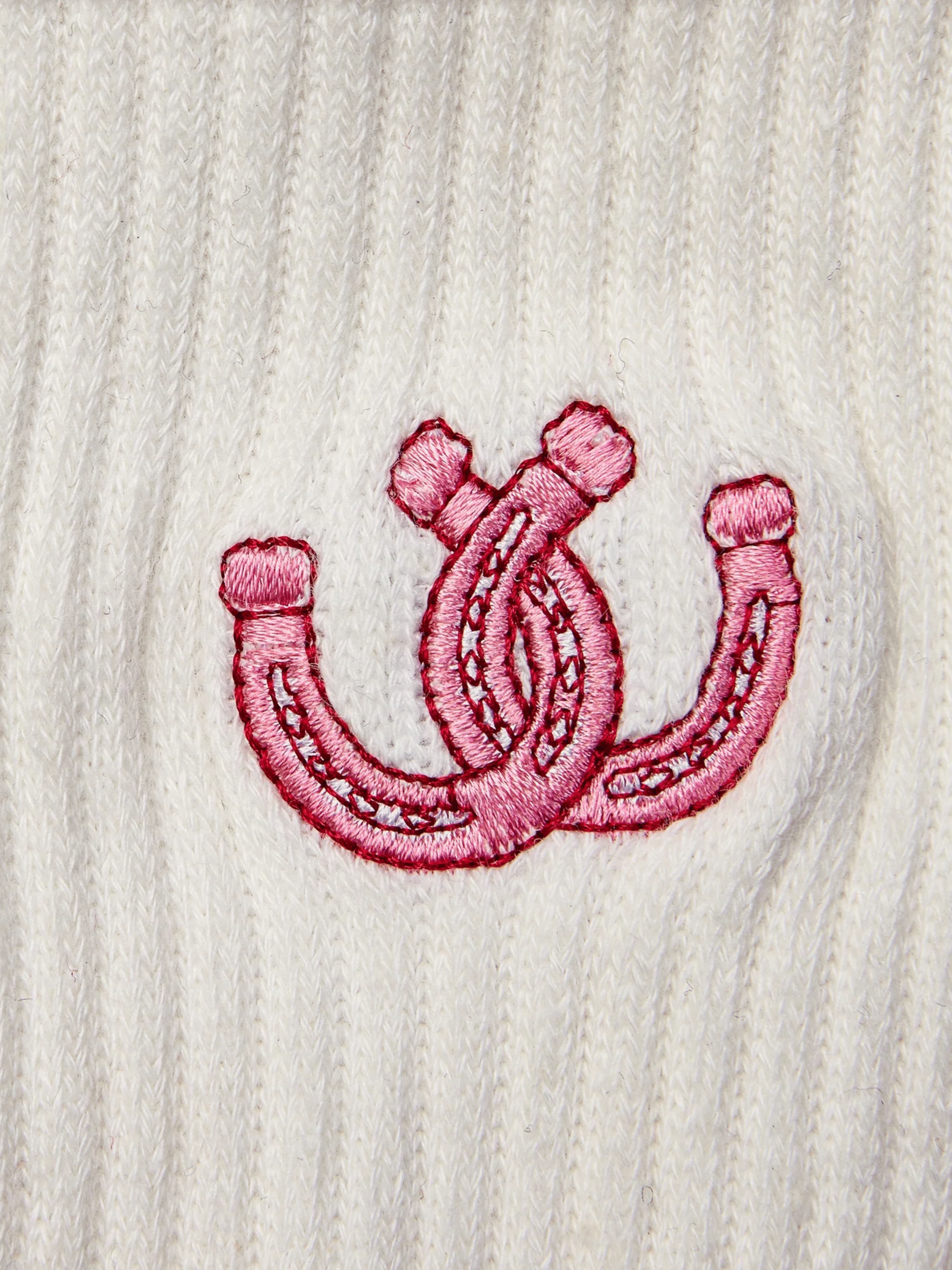 Pink embroidered double horseshoe design on a white textured fabric background