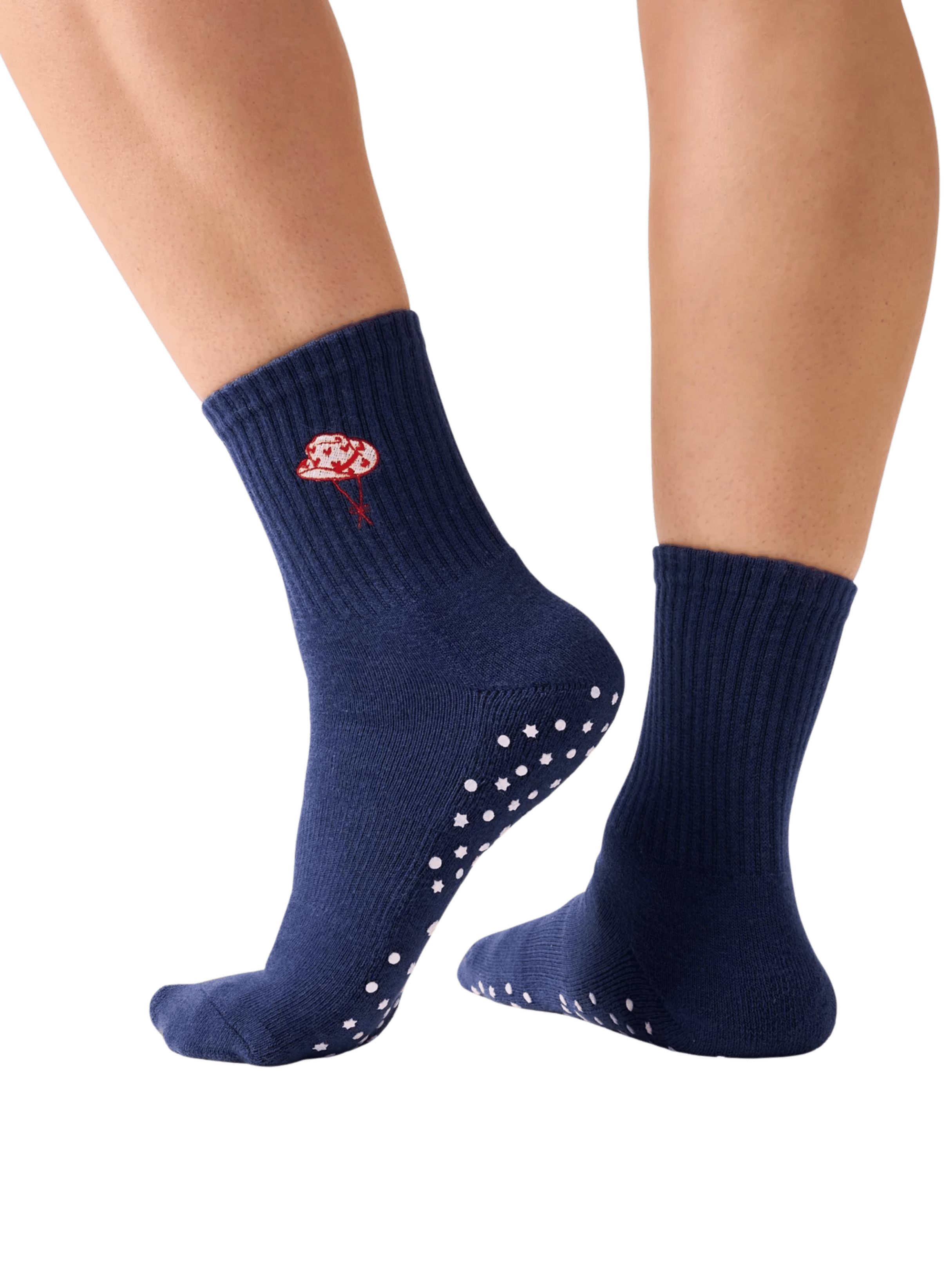 Navy blue socks with white grip dots worn by a person on a transparent background