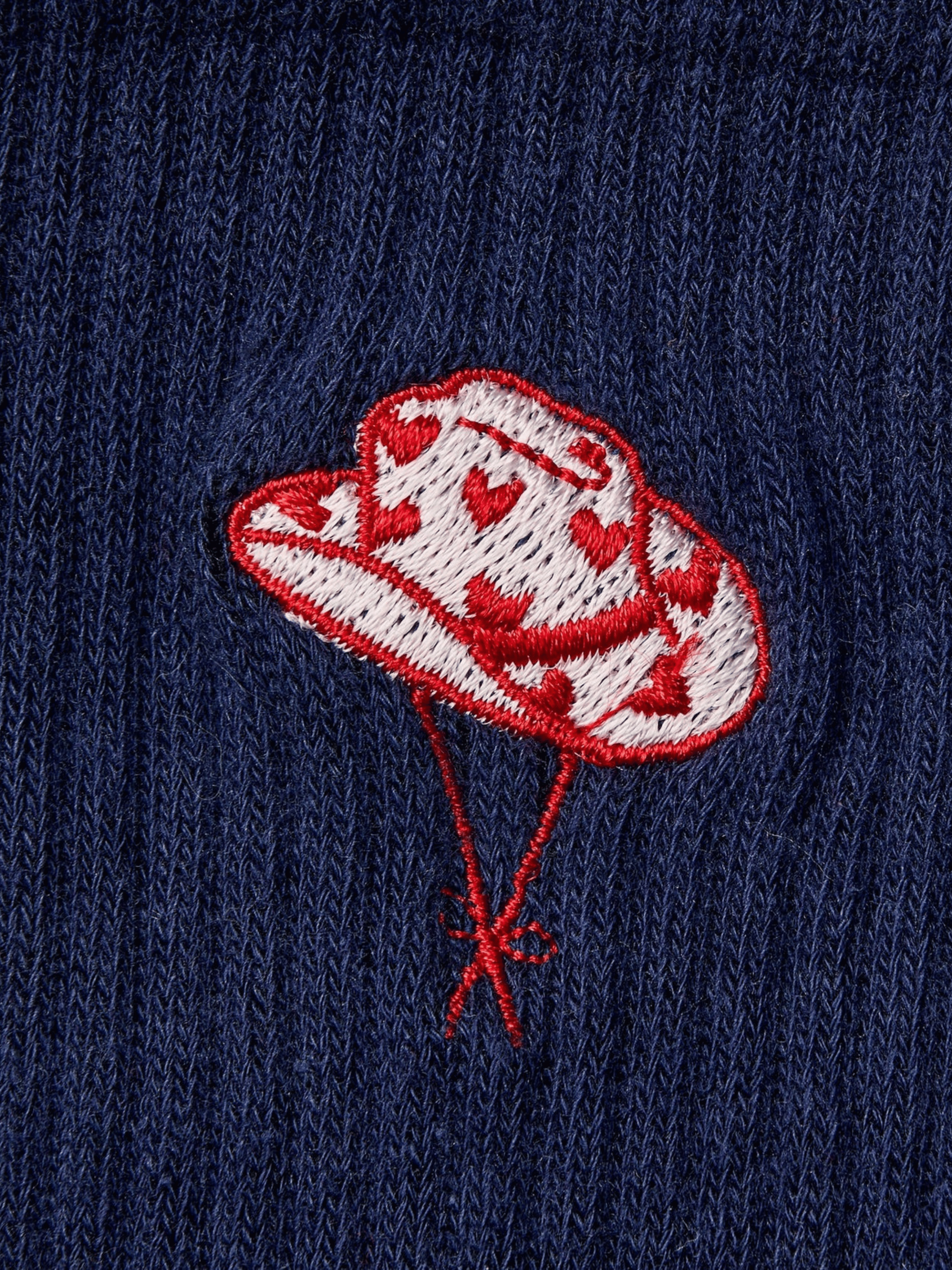 Embroidered design of a cowboy hat on a navy blue fabric background