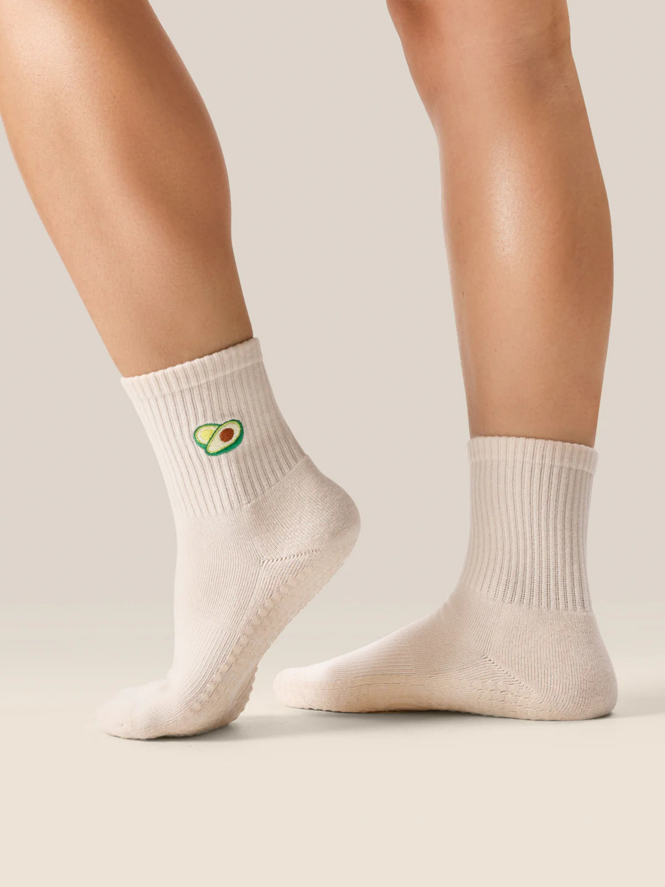 cute Pilates grip socks UK. White socks with avocado design worn by a person on a neutral background
