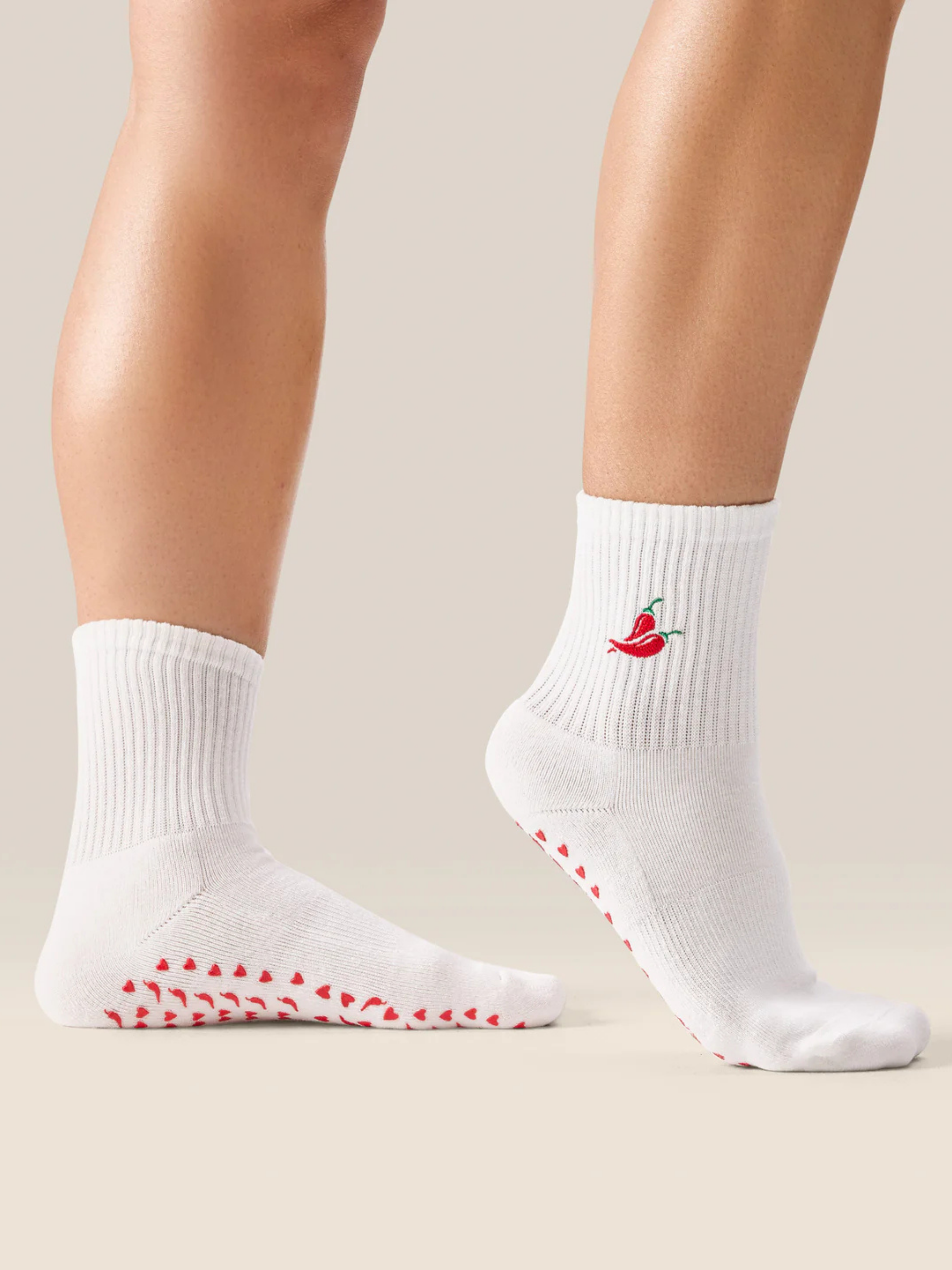 White socks with red patterns and a small logo worn by a person on a neutral background