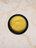 Yellow substance body balm ilapothecary in a black container on a marble surface