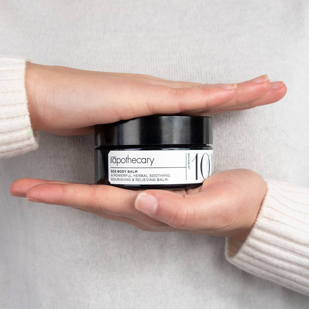 Person holding a jar of itapothecary 10 body balm against a neutral background
