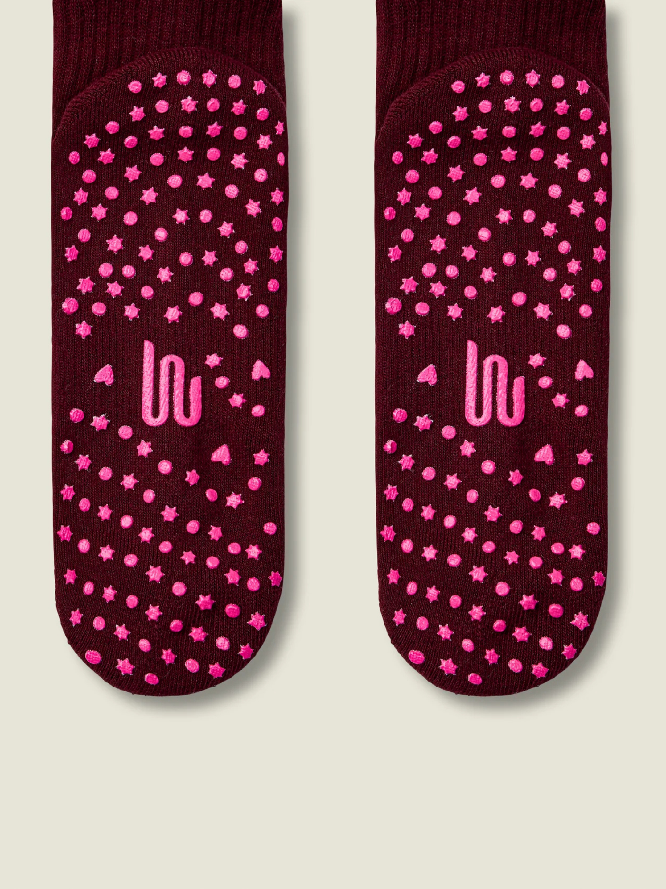 Maroon socks with pink star patterns and 'UU' logo on a beige background