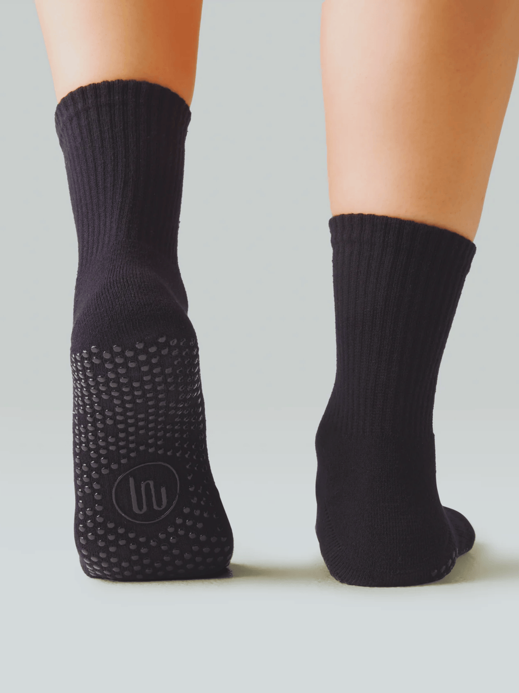 Black socks with textured sole on a neutral background