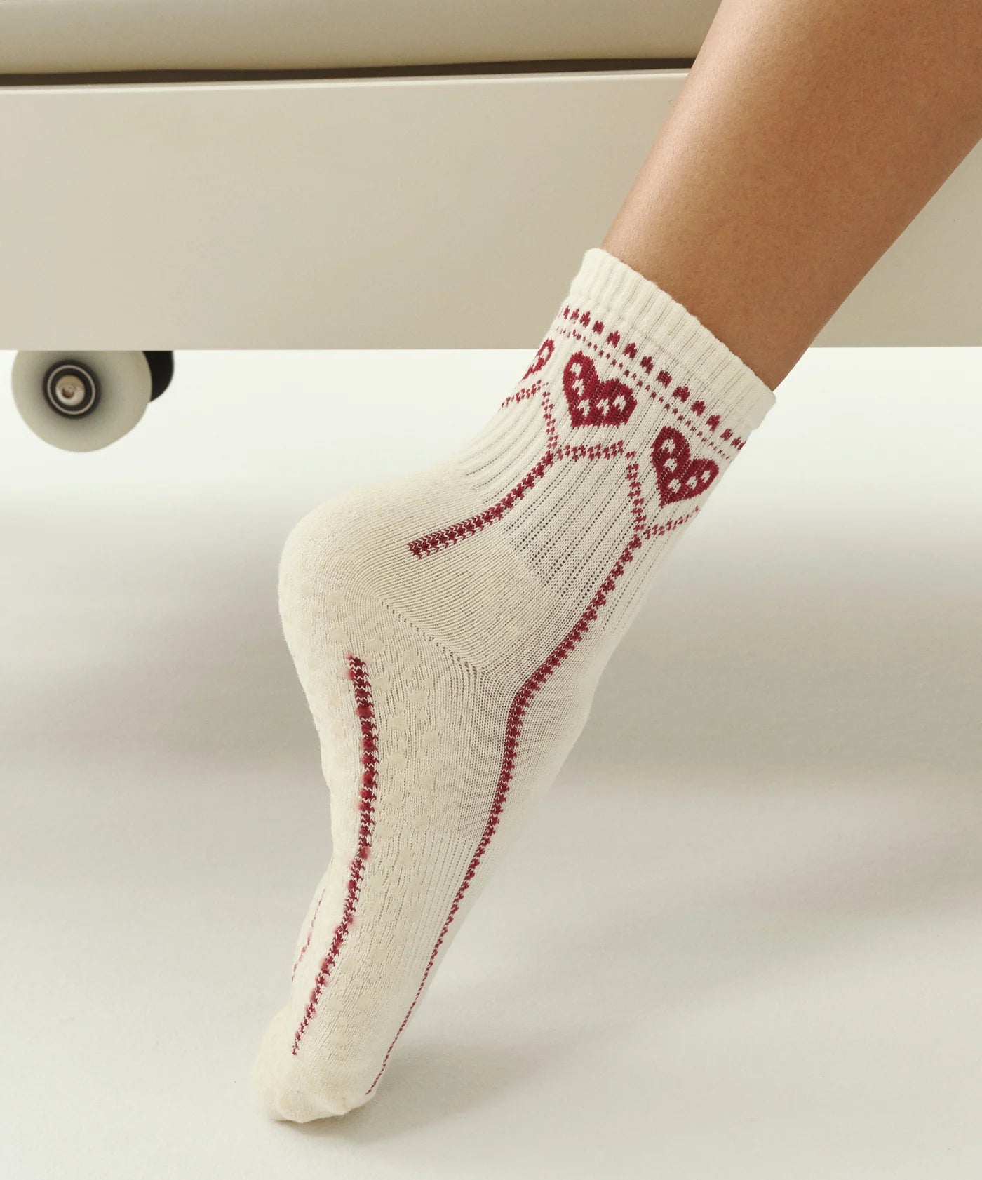 cute Pilates grip socks UK. White socks with red heart patterns worn by a person on a light background